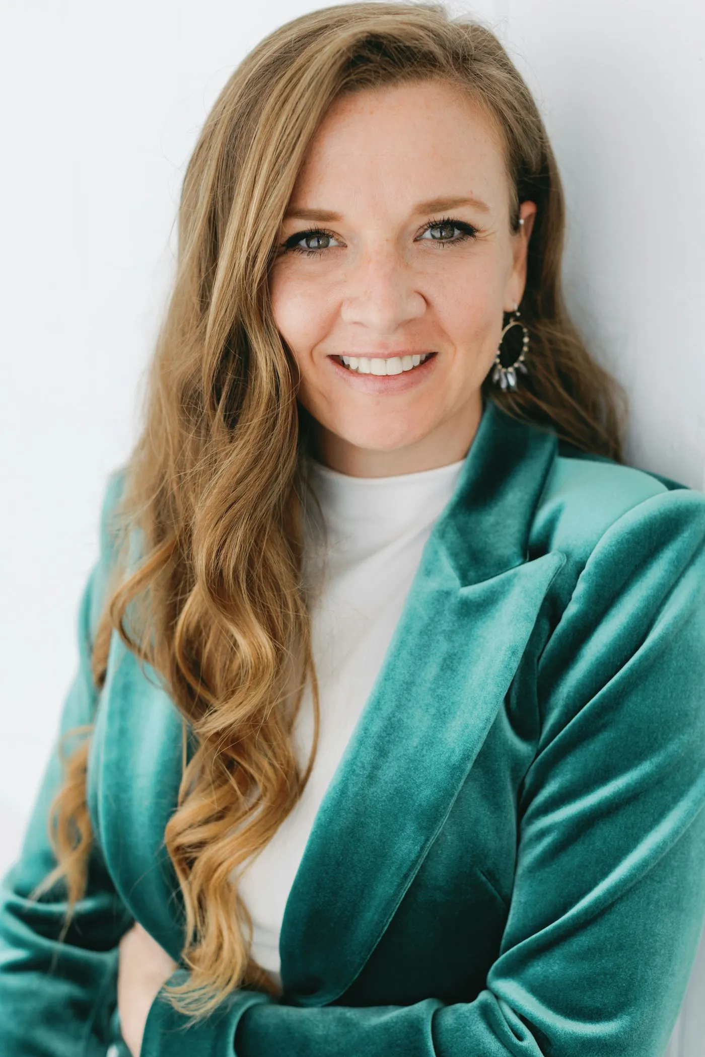 Mujer sonriente con blazer verde posando para una foto comercial