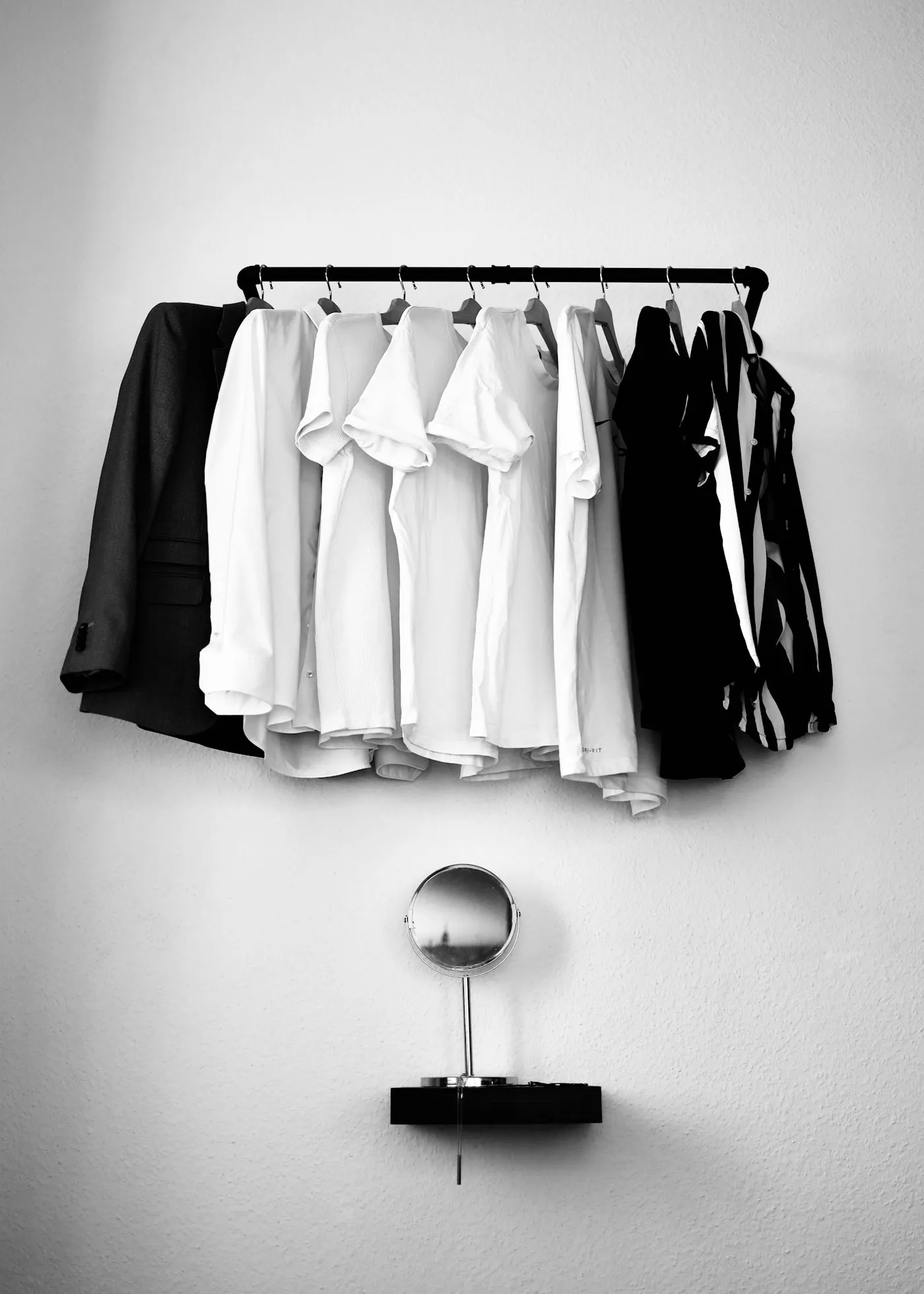 Camisas y camisetas blancas y negras colgadas en un perchero metálico